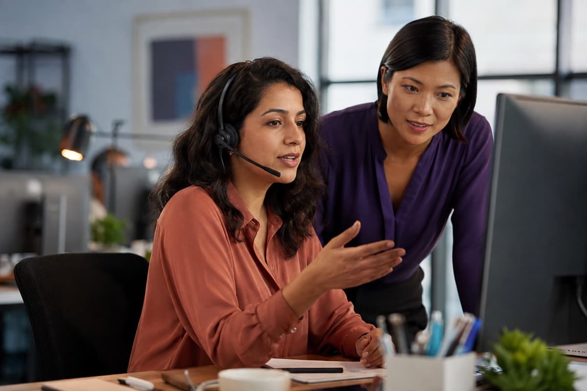 Customer support specialists handling a live service conversation together in a professional support environment